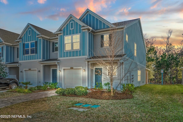 view of front of house featuring a front lawn, board and batten siding, an attached garage, and decorative driveway