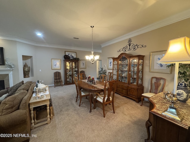 dining space with ornamental molding, an inviting chandelier, a tile fireplace, and light colored carpet