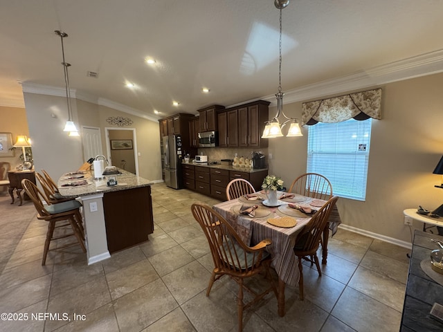 dining room featuring vaulted ceiling, ornamental molding, light tile patterned floors, and baseboards