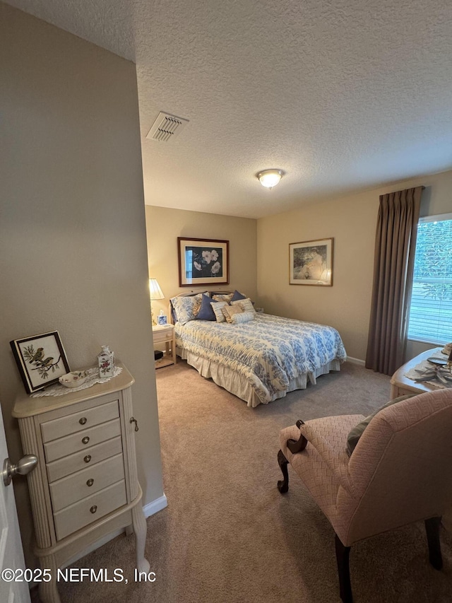 bedroom with baseboards, a textured ceiling, visible vents, and carpet flooring