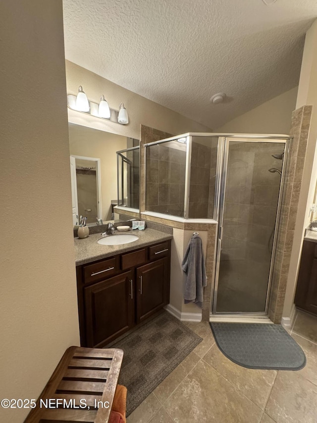 full bathroom with lofted ceiling, a stall shower, a textured ceiling, and vanity