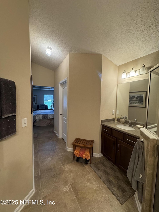 ensuite bathroom with vaulted ceiling, vanity, ensuite bath, a textured ceiling, and baseboards