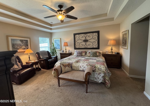 bedroom with baseboards, carpet, a tray ceiling, and a textured ceiling