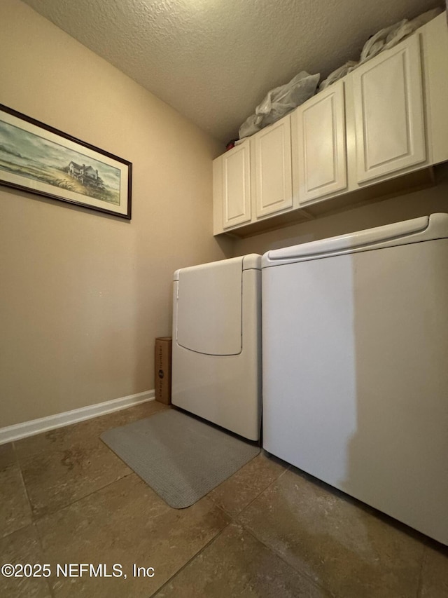 washroom featuring cabinet space, baseboards, separate washer and dryer, and a textured ceiling