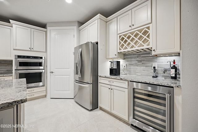 kitchen featuring beverage cooler, light stone counters, stainless steel appliances, and decorative backsplash