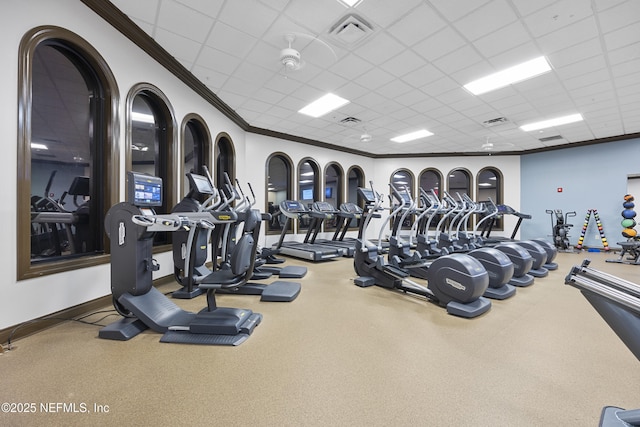 exercise room with a paneled ceiling, visible vents, ornamental molding, and baseboards