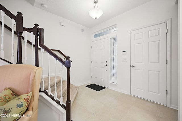 entryway featuring light tile patterned floors, baseboards, and stairway