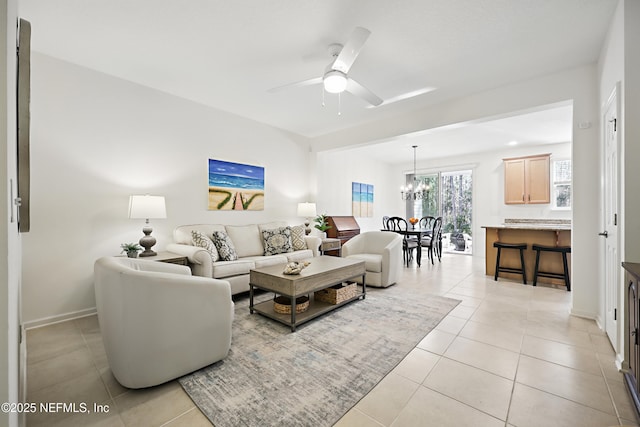 living area featuring light tile patterned flooring and ceiling fan with notable chandelier