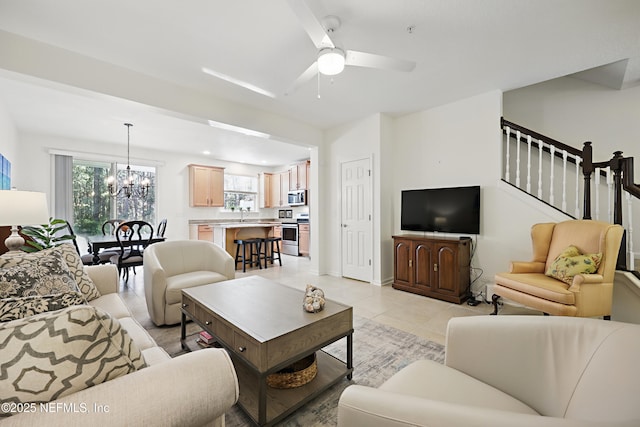 living room featuring ceiling fan with notable chandelier, stairway, and light tile patterned floors