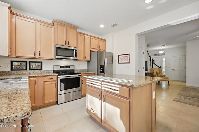 kitchen with appliances with stainless steel finishes, light tile patterned flooring, a sink, and visible vents