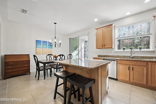 kitchen with decorative light fixtures, a kitchen island, a sink, dishwasher, and a kitchen breakfast bar