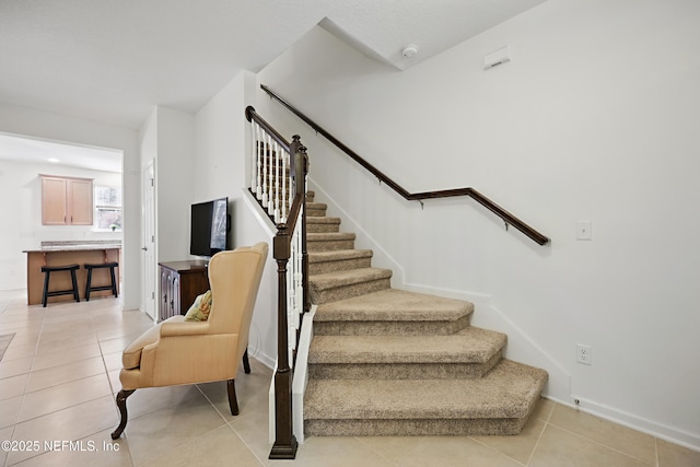 staircase featuring baseboards and tile patterned floors