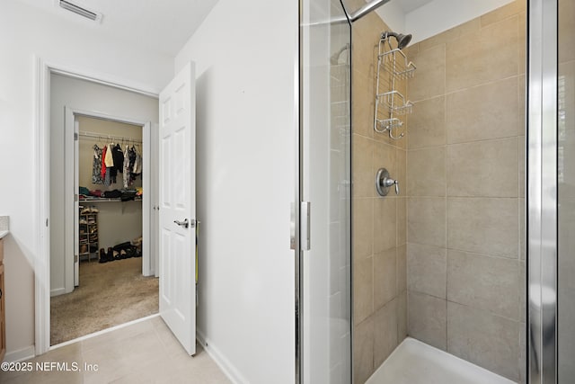 bathroom featuring tile patterned flooring, vanity, visible vents, a spacious closet, and a shower stall