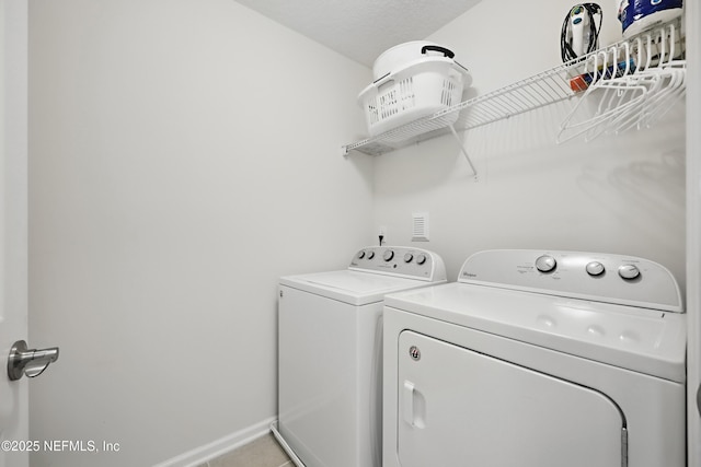 clothes washing area featuring laundry area, light tile patterned flooring, washer and clothes dryer, and baseboards