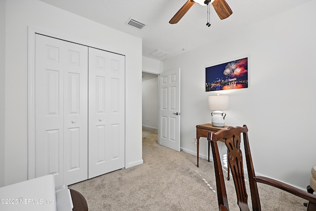 interior space featuring light carpet, baseboards, visible vents, a ceiling fan, and a closet