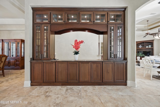 interior space with arched walkways, ornamental molding, a ceiling fan, and built in features