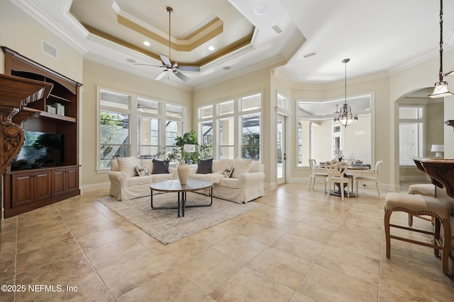 living room with ornamental molding, a tray ceiling, arched walkways, and visible vents