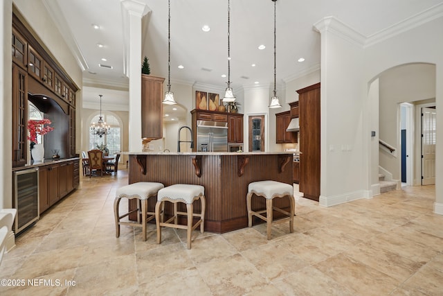 kitchen with built in fridge, arched walkways, a breakfast bar area, hanging light fixtures, and beverage cooler