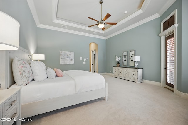 bedroom featuring a tray ceiling, arched walkways, crown molding, and light colored carpet