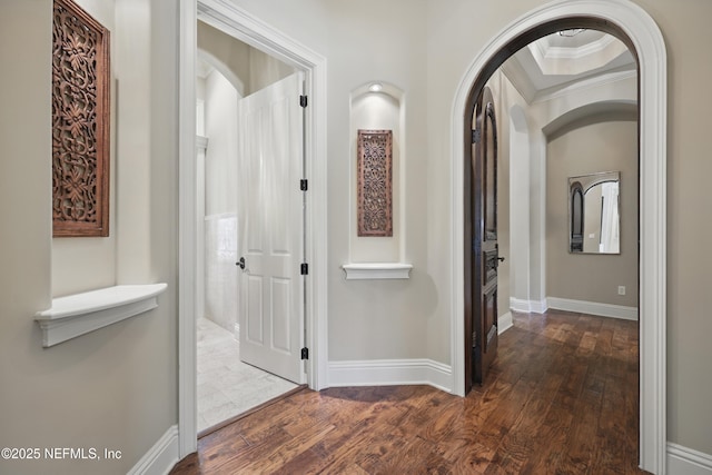 corridor with ornamental molding, hardwood / wood-style flooring, and baseboards