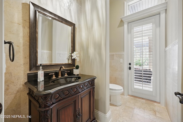 bathroom with tile walls, toilet, and vanity