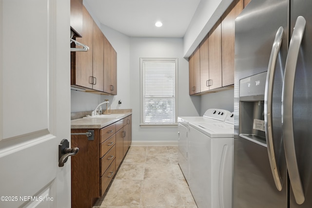 laundry room featuring washer and clothes dryer, light tile patterned floors, cabinet space, a sink, and baseboards