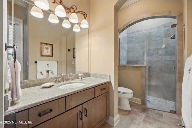 bathroom featuring toilet, a stall shower, baseboards, and vanity