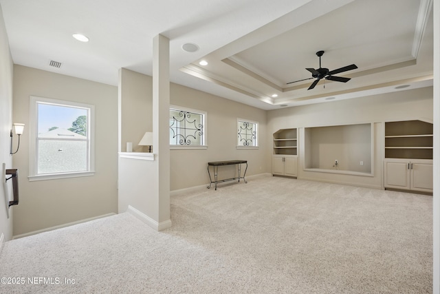 empty room featuring built in features, carpet floors, a raised ceiling, visible vents, and baseboards