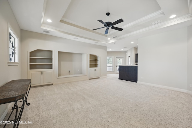 living area featuring light carpet, baseboards, a tray ceiling, and ornamental molding