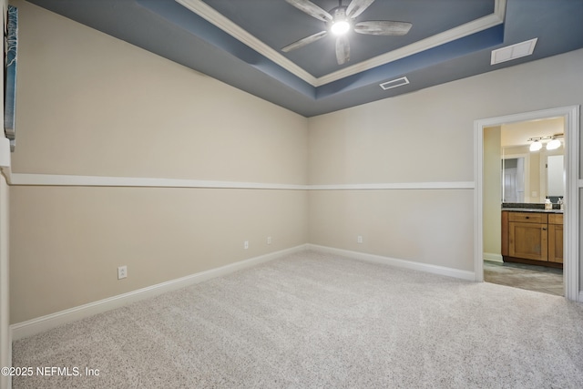 carpeted spare room with baseboards, visible vents, a raised ceiling, and ornamental molding