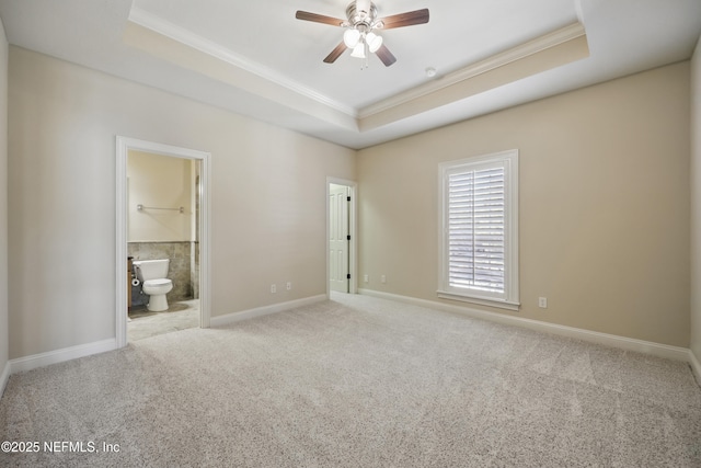 unfurnished bedroom featuring carpet floors, a raised ceiling, crown molding, and baseboards