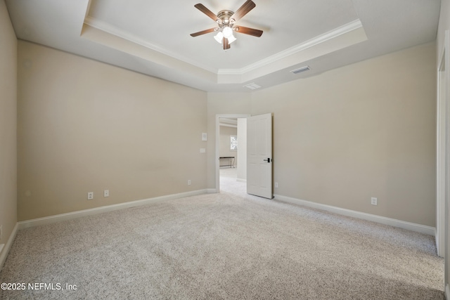 unfurnished room with a tray ceiling, crown molding, visible vents, carpet flooring, and ceiling fan