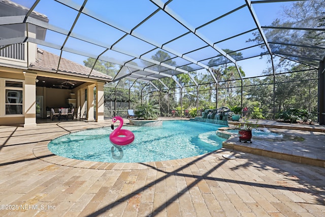 view of pool featuring ceiling fan, glass enclosure, a patio area, and a pool with connected hot tub