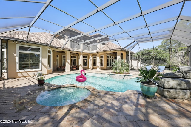 view of pool featuring a lanai, a pool with connected hot tub, and a patio