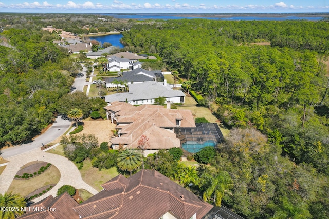 drone / aerial view with a water view, a residential view, and a view of trees