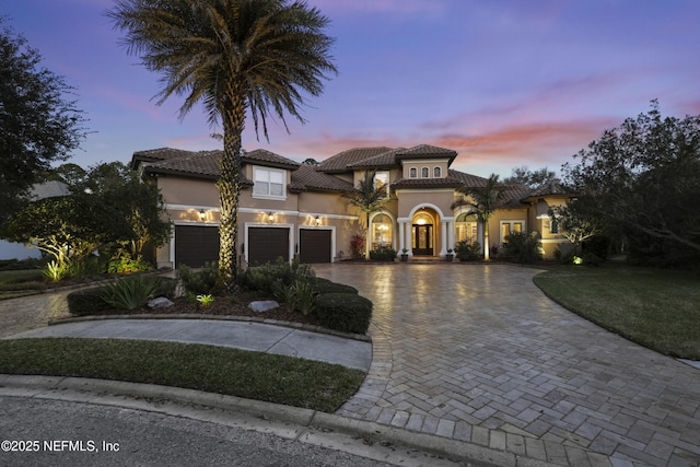 mediterranean / spanish-style house with decorative driveway, an attached garage, and stucco siding