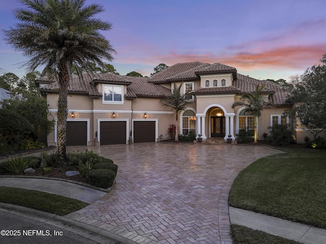 mediterranean / spanish house with a tiled roof, a front lawn, decorative driveway, and stucco siding