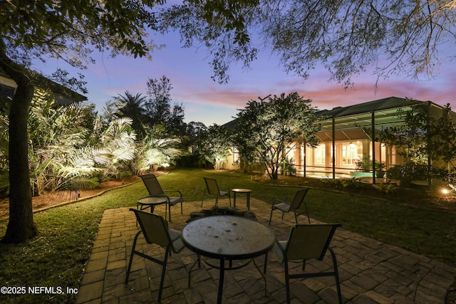 patio terrace at dusk with a yard and glass enclosure