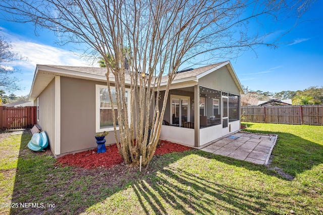 rear view of house with a lawn, a patio, and a sunroom