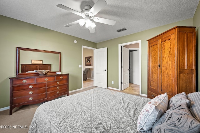 bedroom featuring a textured ceiling, light carpet, and ceiling fan