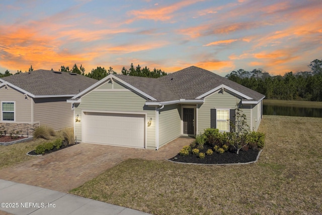 single story home featuring a yard, decorative driveway, a garage, and roof with shingles