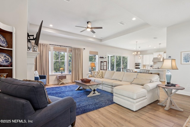 living room with recessed lighting, a raised ceiling, and light wood-style floors