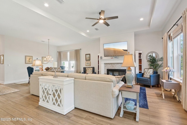 living room featuring light wood finished floors, plenty of natural light, and a raised ceiling