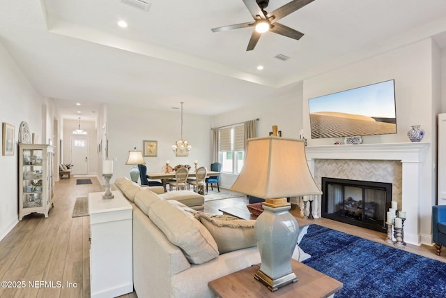 living room featuring light wood-style floors, recessed lighting, a fireplace, and ceiling fan with notable chandelier