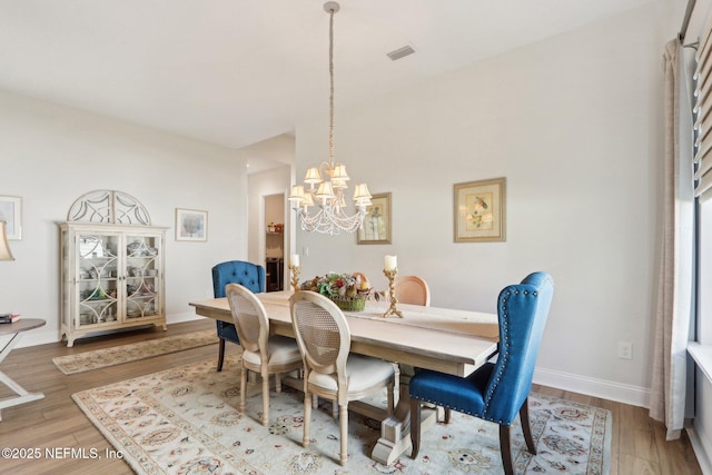 dining area with an inviting chandelier, visible vents, baseboards, and wood finished floors