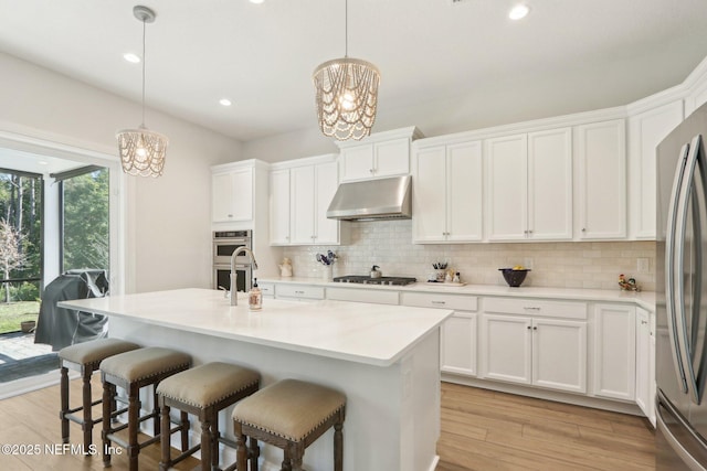 kitchen with under cabinet range hood, white cabinetry, pendant lighting, and light countertops