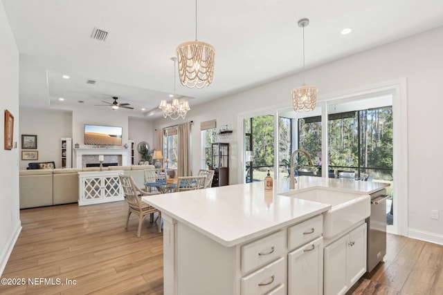 kitchen with pendant lighting, light countertops, visible vents, open floor plan, and a kitchen island with sink