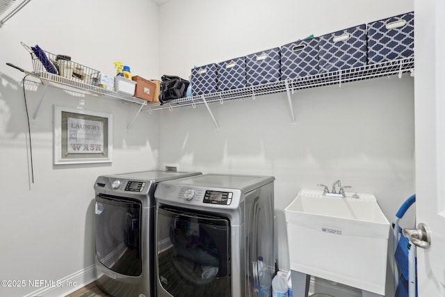 laundry area featuring laundry area, baseboards, washer and dryer, and a sink