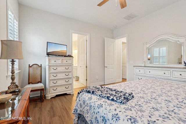 bedroom featuring multiple windows, connected bathroom, visible vents, and wood finished floors