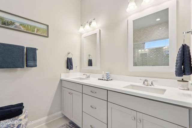 bathroom featuring tiled shower, a sink, baseboards, and double vanity